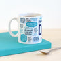 White mug with blue text on a teal coaster with a spoon
